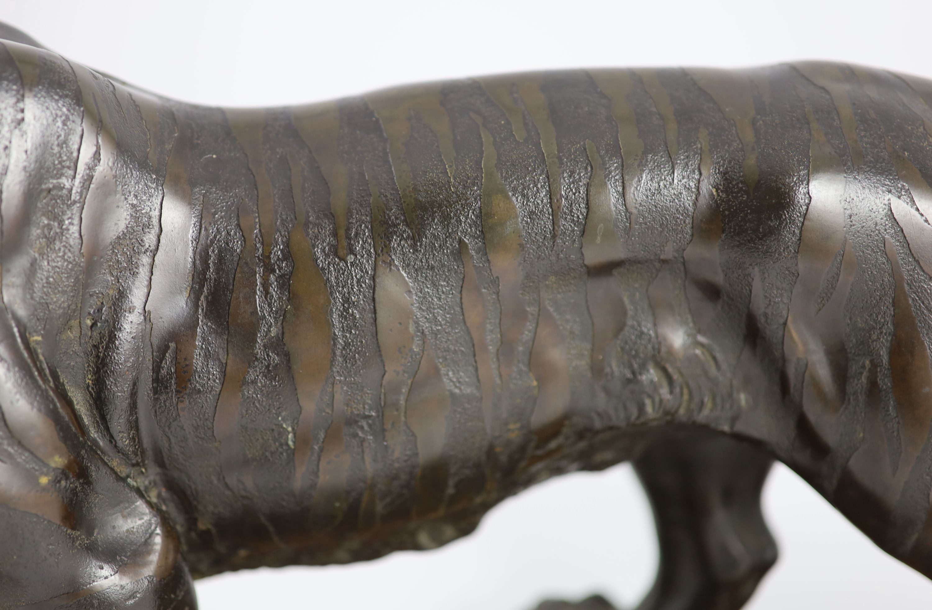 A large Japanese Meiji bronze model of a stalking tiger, Meiji period, 58.5 cm long, wood stand